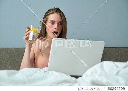 Beautiful emotional woman sitting in bed using laptop computer 68294209