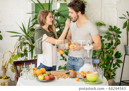 beautiful fair-haired girl giving an orange to her handsome bear 68294563