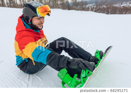 handsome positive man preparing for snowboarding handsome positive man preparing for snowboarding 68295271