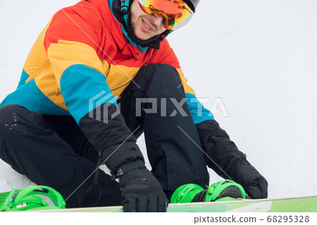 young man learning to put on snowboard 68295328