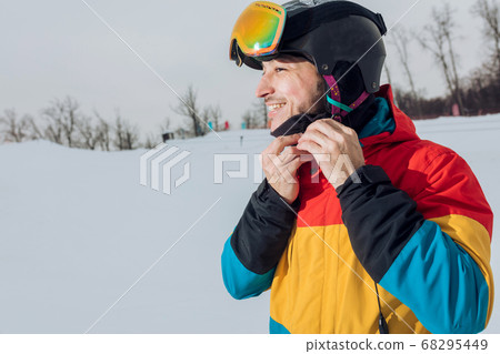 Young cheerful snowboarder putting on his sportswear Young cheerful snowboarder putting on his sportswear 68295449