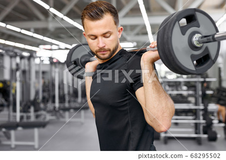 caucasian athletic man pumping up muscles with barbells 68295502