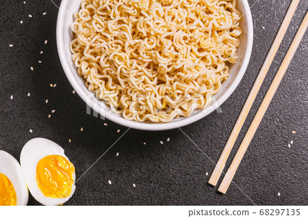 noodles in a plate with sesame seeds bamboo sticks, boiled eggs on a black table close-up. flat ley. copy space. noodles in a plate with sesame seeds bamboo sticks, boiled eggs on a black table close-up. flat ley. copy space. 68297135