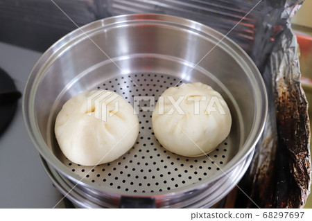 Two meat buns arranged in a steamer 68297697