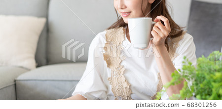 年輕女子在客廳橫幅大小喝茶時讀雜誌 68301256