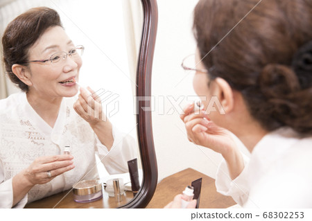 Senior woman putting on makeup 68302253