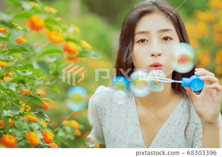 woman is blowing bubbles in the garden 68303396