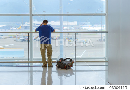 Back view of traveling man standing near window at the international airport Back view of traveling man standing near window at the international airport 68304115