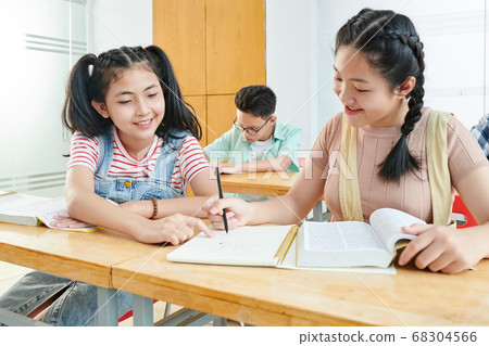 Girl helping classmate with project 68304566