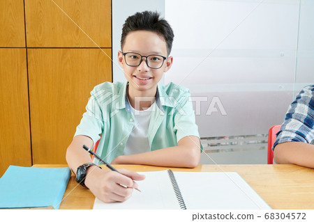 Teenage boy writing in copybook Teenage boy writing in copybook 68304572
