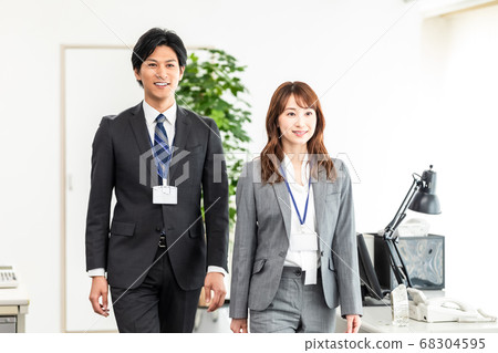 Male and female employees walking in the office Male and female employees walking in the office 68304595