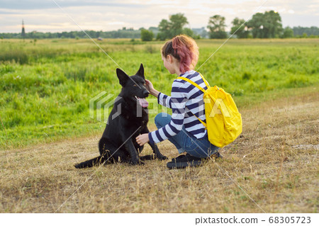 Teen girl pet owner playing and talking with big black shepherd dog Teen girl pet owner playing and talking with big black shepherd dog 68305723