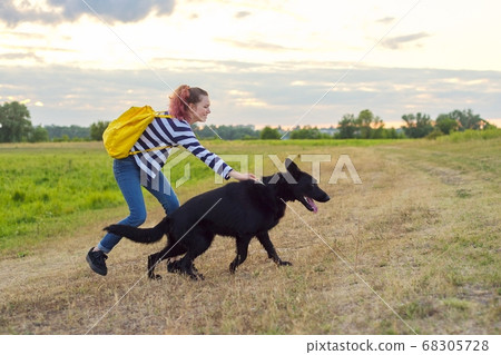 Teen girl pet owner playing and talking with big black shepherd dog Teen girl pet owner playing and talking with big black shepherd dog 68305728
