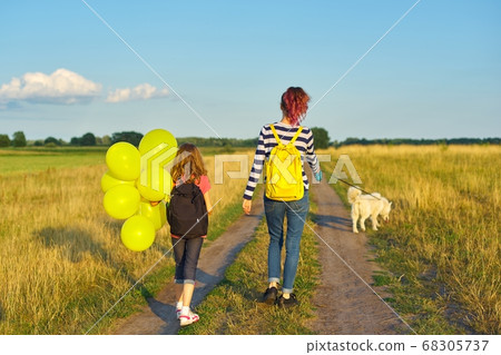 Children two girls walking along country road with dog and balloon, back view Children two girls walking along country road with dog and balloon, back view 68305737