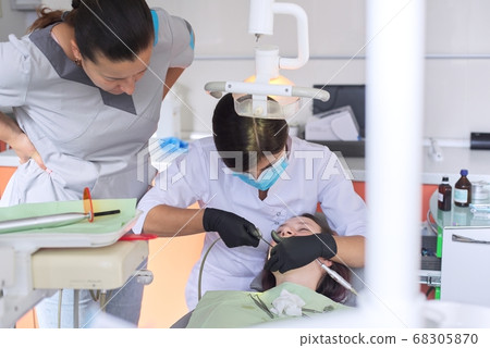 Experienced doctor dentist advising young intern of treating patient Experienced doctor dentist advising young intern of treating patient 68305870