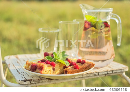 Cake with berries and jug with strawberry mint drink in summer sunny meadow Cake with berries and jug with strawberry mint drink in summer sunny meadow 68306538