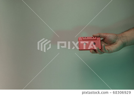 Hand holding red audio cassette tape in the color 68306929