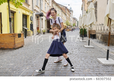 Two girls sisters having fun on the way to school Two girls sisters having fun on the way to school 68307502