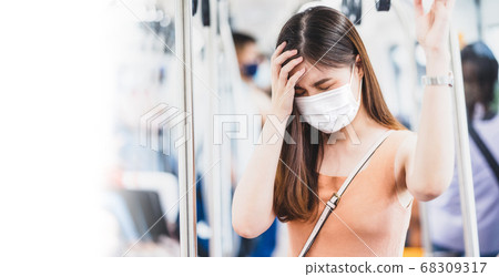 Young Asian woman passenger wearing surgical mask and Having a headache in subway train when traveling in big city at Covid19 outbreak, Infection and Pandemic,new normal and illness prevention concept 68309317