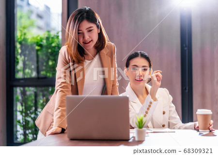 Two asian businesswomen working with the partner business via technology laptop in modern meeting room, office or working space, coffee break, partner and colleague concept. 68309321