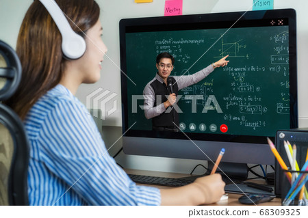 Rear View of Asian student learning with teacher over the physics formular in thai laguage on black board via video call conference when Covid-19 pandemic, education and Social distancing concept 68309325