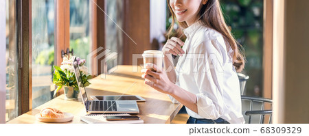Banner of Portrait Young Asian woman holding and drinking a cup of coffee and working with technology laptop at a coffee shop.freelancer and entrepreneur working by connecting to internet via computer 68309329