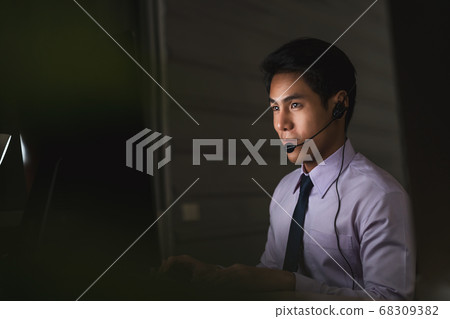 Asian male customer care service smiling and working hard late in night shift at office, call center department,worker and overtime, 7 days 24 hour support,teamwork with colleagues for success concept Asian male customer care service smiling and working hard late in night shift at office, call center department,worker and overtime, 7 days 24 hour support,teamwork with colleagues for success concept 68309382
