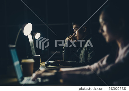 Asian businesswoman and businessman working hard late together with technology computer in office, customer service and call center, team work with colleagues for success achievement project concept 68309388