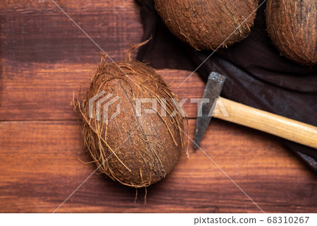 Open coconut and a small hammer on a wooden table 68310267