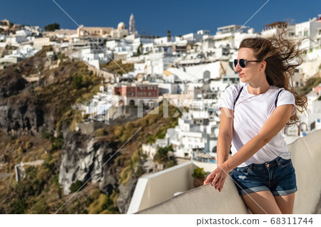 Happy smiling woman tourist traveling on luxury cruise in Mediterranean, Greece, Santorini. Background architecture island sea sky Happy smiling woman tourist traveling on luxury cruise in Mediterranean, Greece, Santorini. Background architecture island sea sky 68311744