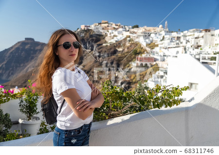 Happy smiling woman tourist traveling on luxury cruise in Mediterranean, Greece, Santorini. Female with folded arms, background architecture island sea sky 68311746