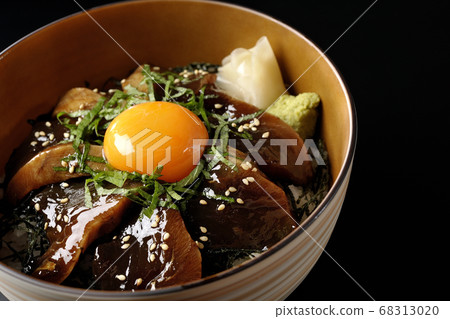 Pickled bowl of bonito with chopped seaweed, large leaves, gari, wasabi and egg yolk on the center (black background) 68313020