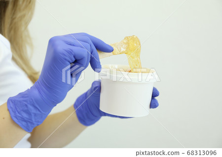 Young woman holding liquid yellow paste for 68313096