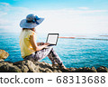 Business woman sitting by the sea with laptop 68313688