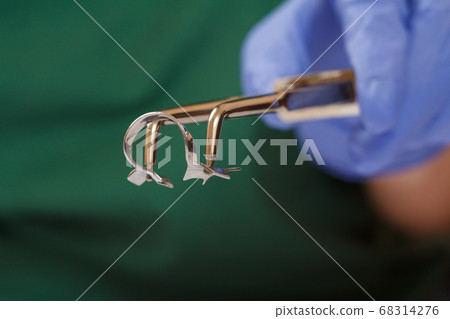 Dentist's hand in glove with dental tongs and 68314276