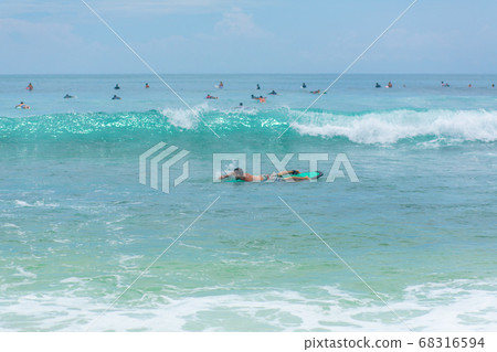 The guy is swimming on the surf board on the 68316594