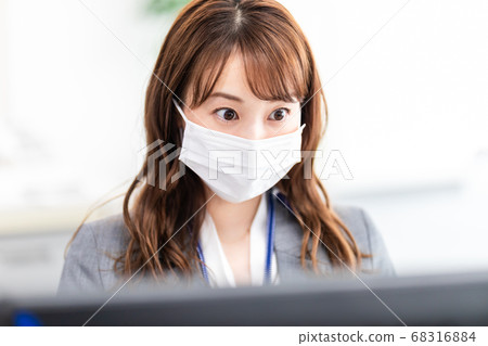A woman working with a mask in the office A woman working with a mask in the office 68316884