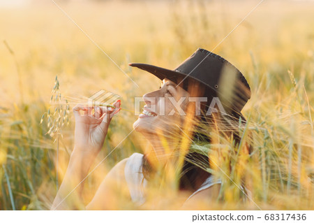 Woman farmer in cowboy hat at agricultural field on sunset 68317436