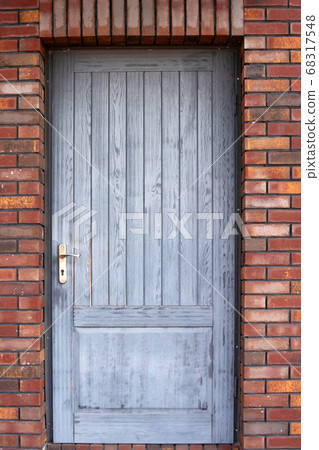 Old wooden front door of a red brick house 68317548