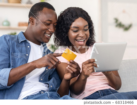Closeup of black couple making purchases online, holding digital tablet 68318466