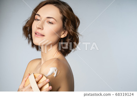 Beautiful young woman using body massage brush Beautiful young woman using body massage brush 68319124