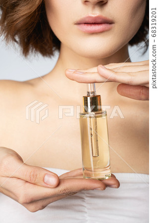 Young woman holding bottle of vitamin face serum Young woman holding bottle of vitamin face serum 68319201