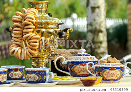 Golden samovar on the table with tea set Golden samovar on the table with tea set 68319599