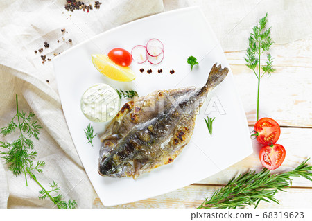 Fried fish with vegetables on wooden table Fried fish with vegetables on wooden table 68319623