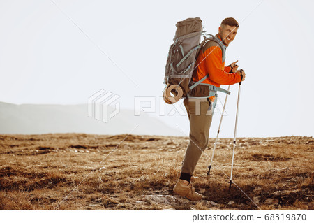 Man traveler with trekking sticks going up the mountain Man traveler with trekking sticks going up the mountain 68319870