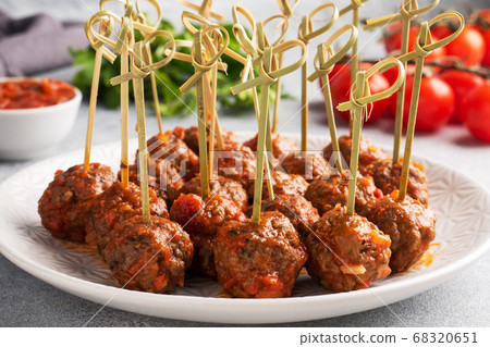 Beef meatballs stewed in tomato sauce on a plate on barbecue skewers. Light concrete background. Beef meatballs stewed in tomato sauce on a plate on barbecue skewers. Light concrete background. 68320651