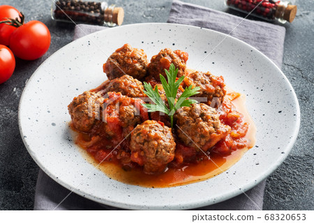 Beef meatballs stewed in tomato sauce on a plate. Dark concrete background. Beef meatballs stewed in tomato sauce on a plate. Dark concrete background. 68320653