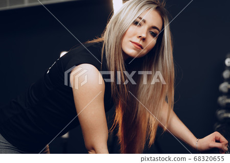 Portrait of a young woman in sportswear posing in a gym Portrait of a young woman in sportswear posing in a gym 68320655