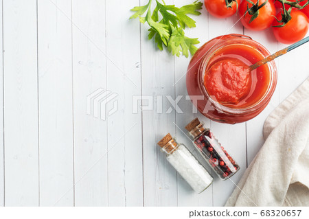 Tomatoes in their own juice or Tomato paste in a glass jar and fresh tomatoes on a white wooden table. Copy space Tomatoes in their own juice or Tomato paste in a glass jar and fresh tomatoes on a white wooden table. Copy space 68320657