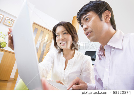 看著一台筆記本電腦的中年夫婦 68320874